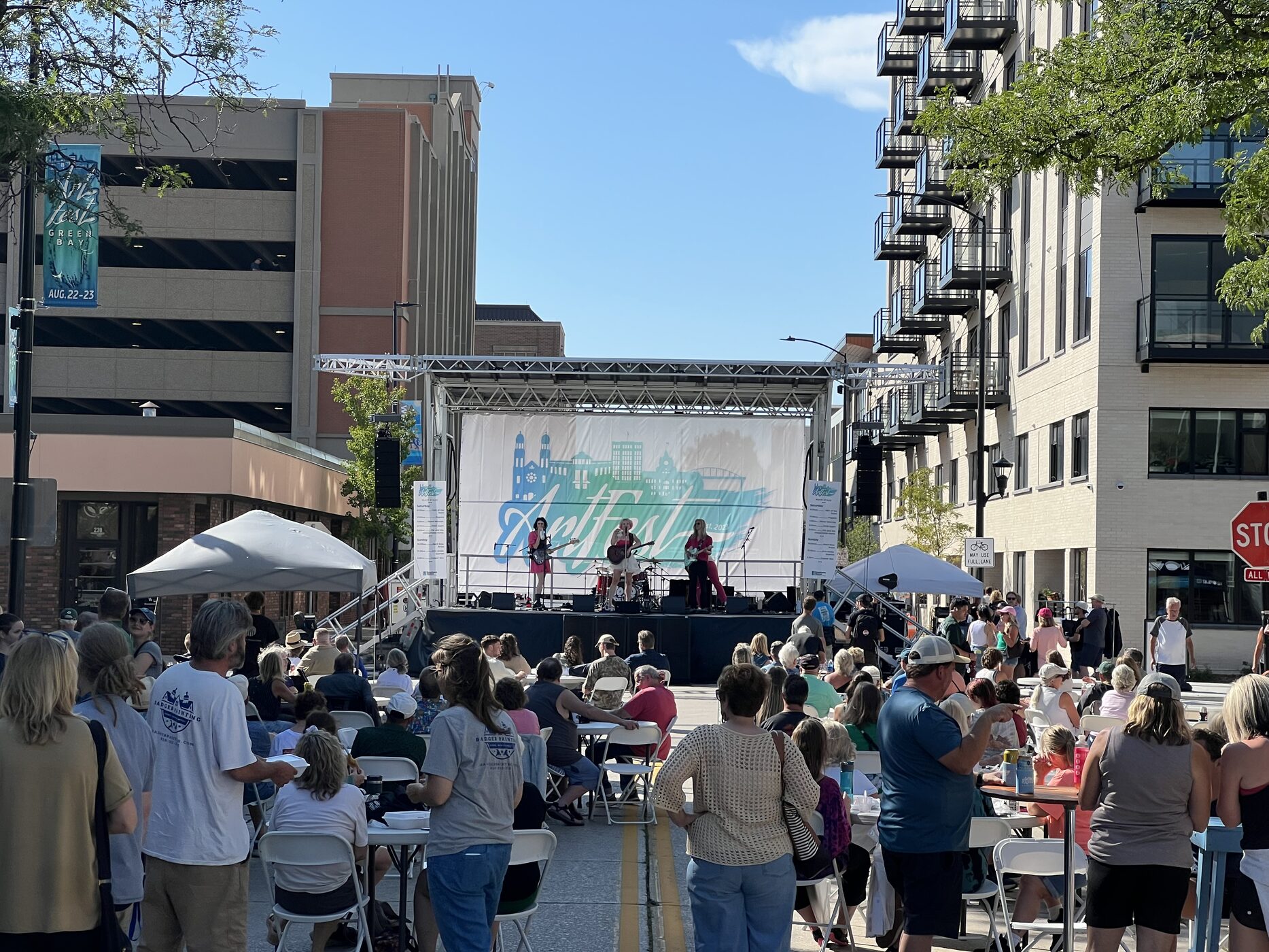 A daytime crowd watching a band on an outdoor stage at ArtFest Green Bay