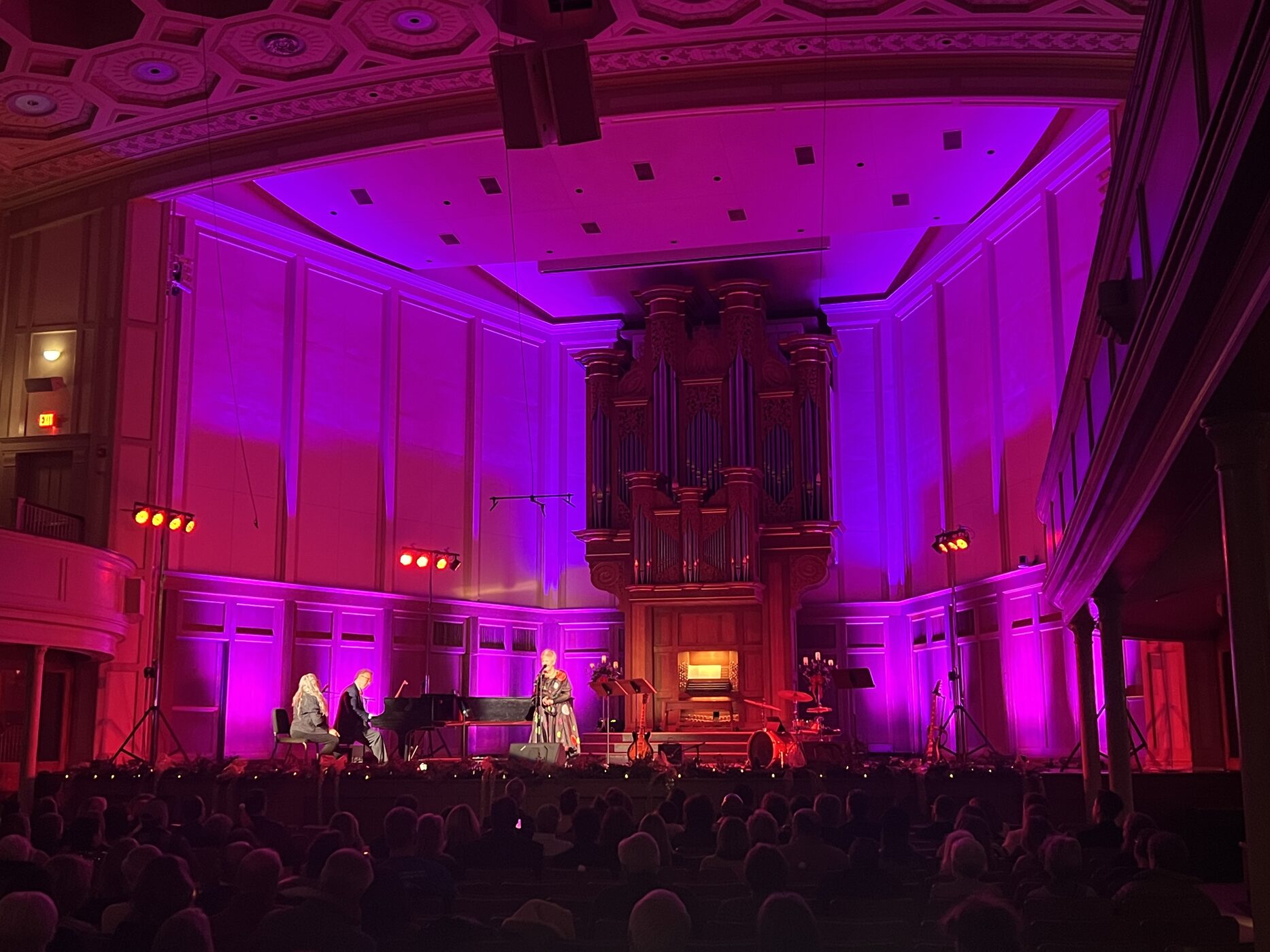 A historic concert hall washed in magenta and red theatrical light