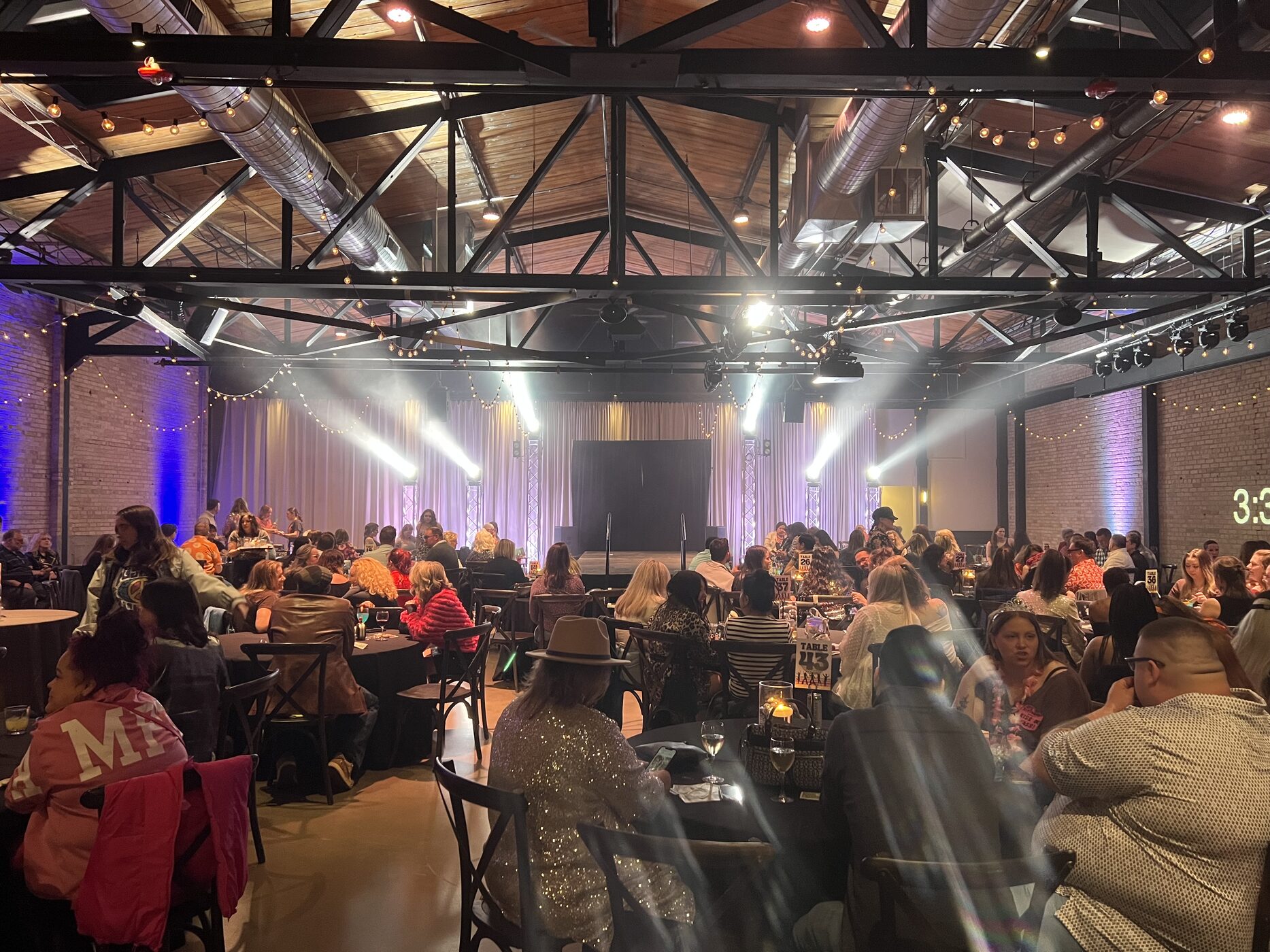 A transformed event room at Gather on Broadway with theatrical lighting and guests