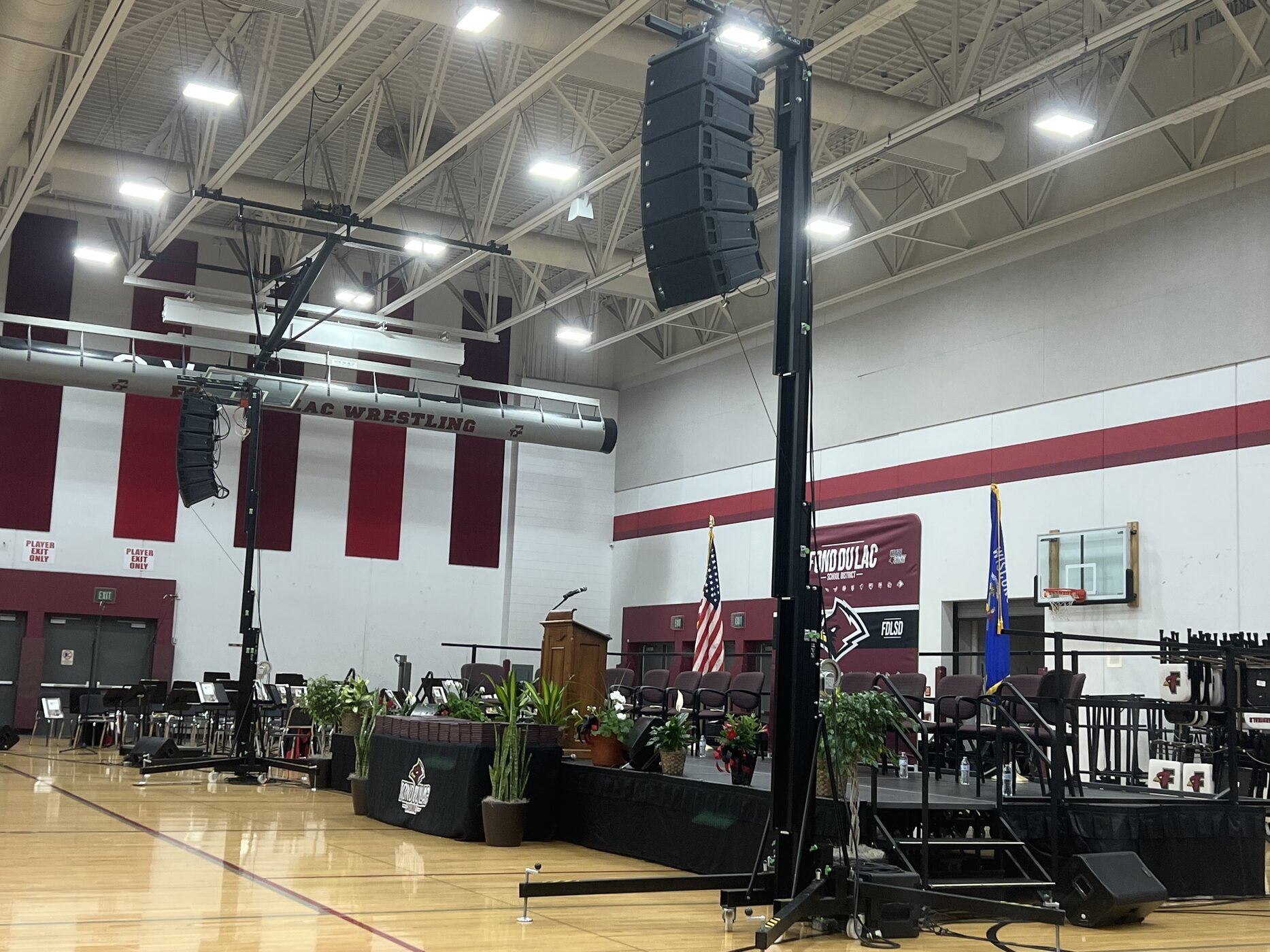 A large flown audio system set up for a high school graduation in a gymnasium