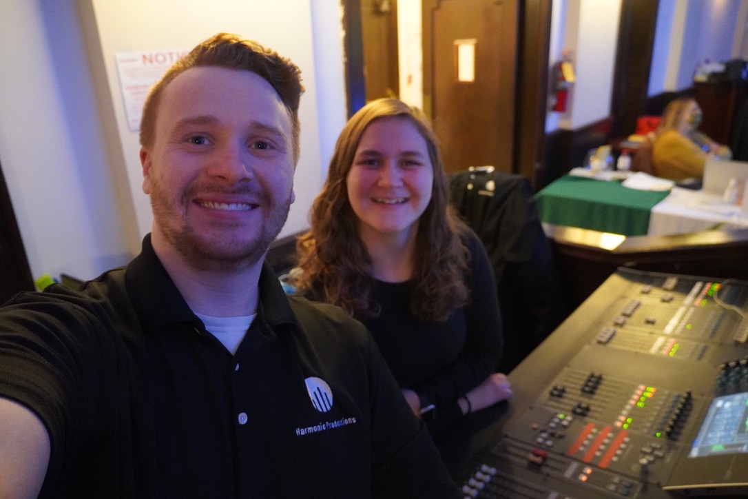 Two Harmonic Productions crew members at an audio console during an event